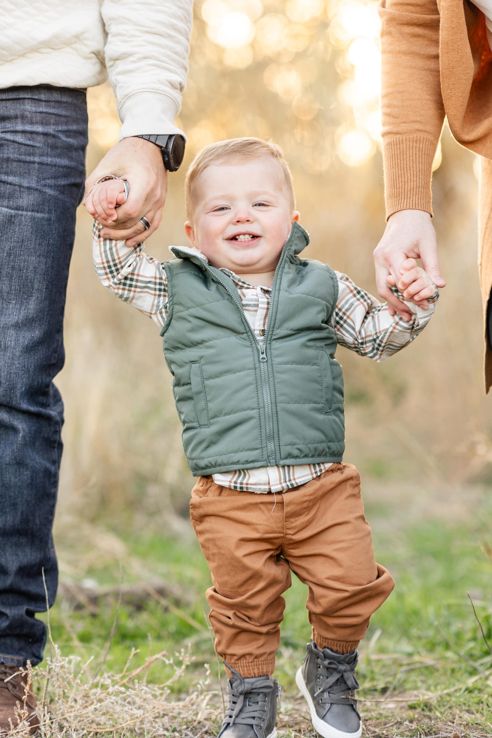 boy holding parents hands during riverton family photo session
